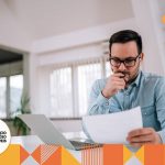 Homem sentado e pensativo, olhando informações em um papel.