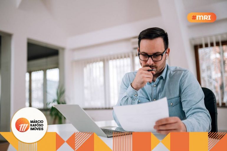 Homem sentado e pensativo, olhando informações em um papel.