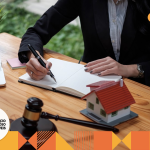 advogada escrevendo algo em um caderno. em cima da mesa, um martelo de direito, notebook, caneca, planta. imóveis de herança